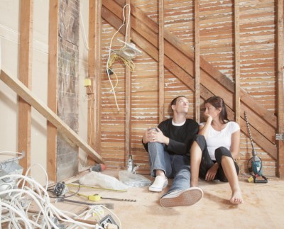Couple sitting against wall of unrenovated room